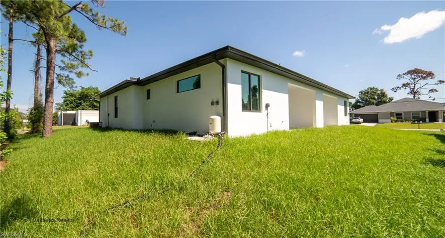 Back of property featuring a lawn and stucco siding