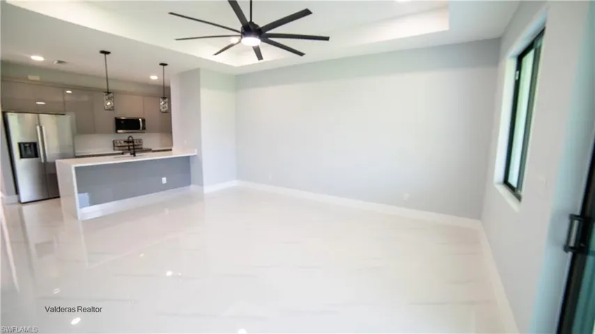 Unfurnished living room with recessed lighting, a raised ceiling, and a ceiling fan