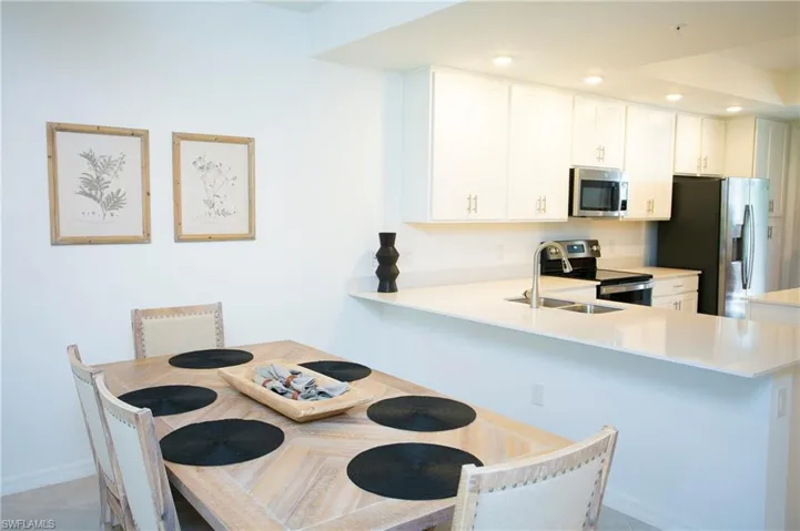 Kitchen with recessed lighting, stainless steel appliances, a peninsula, light stone countertops, and white cabinets