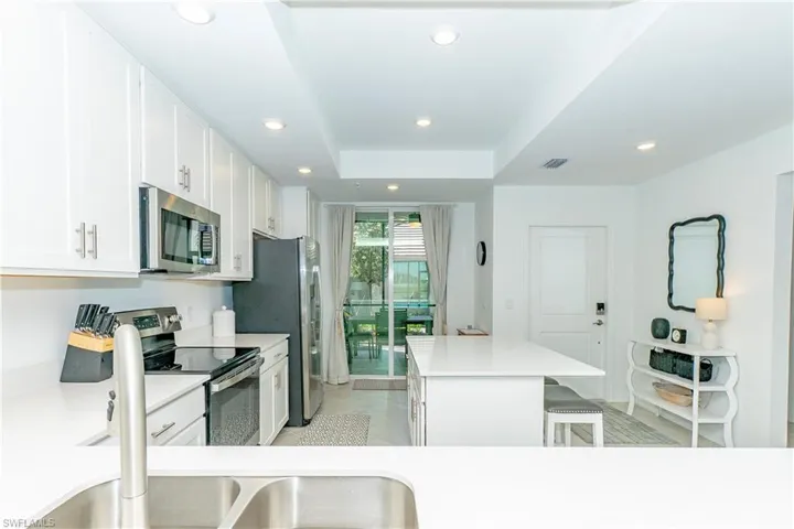 Kitchen featuring stainless steel appliances, a kitchen island, recessed lighting, white cabinetry, and a kitchen breakfast bar
