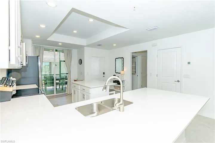 Kitchen featuring recessed lighting, a tray ceiling, white cabinetry, a kitchen island, and light countertops