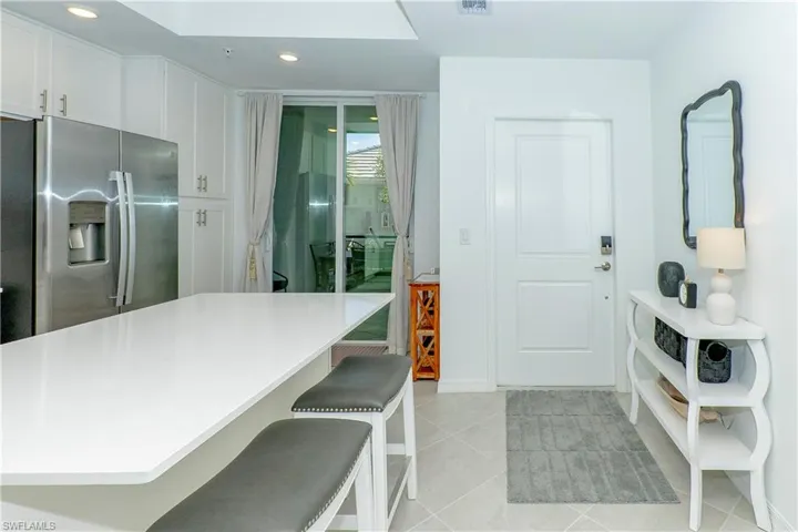 Kitchen featuring stainless steel fridge with ice dispenser, a breakfast bar area, light countertops, white cabinetry, and recessed lighting