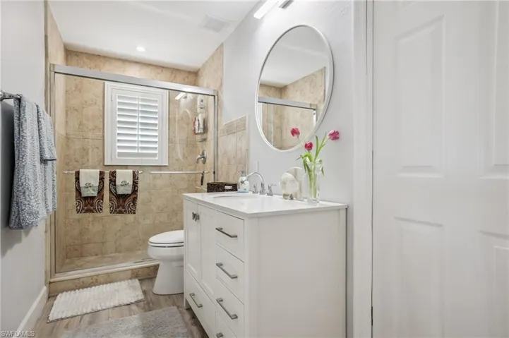 Full shared bath featuring vanity, a shower stall, and light wood-style floors