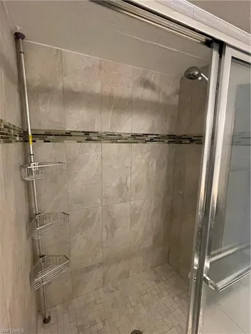 Tiled shower enclosure featuring a mosaic accent band and a sliding glass door