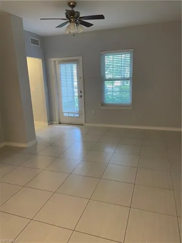 Spacious room featuring light-toned tile flooring, neutral wall paint, and a ceiling fan with integrated lighting