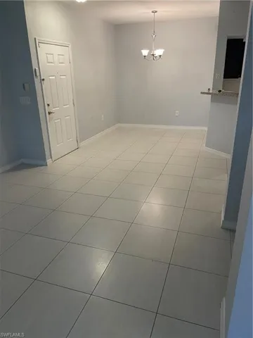 Expansive interior room featuring light-toned tile flooring, neutral wall tones, and a decorative ceiling light fixture