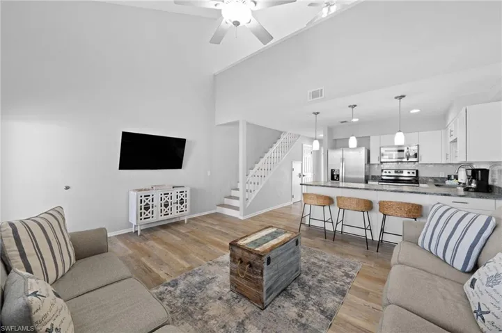 Living room with light wood-style floors, stairs, and ceiling fan