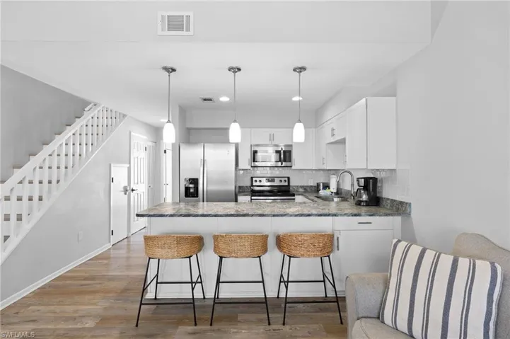 Kitchen featuring appliances with stainless steel finishes, backsplash, dark wood-style flooring, a peninsula, and recessed lighting