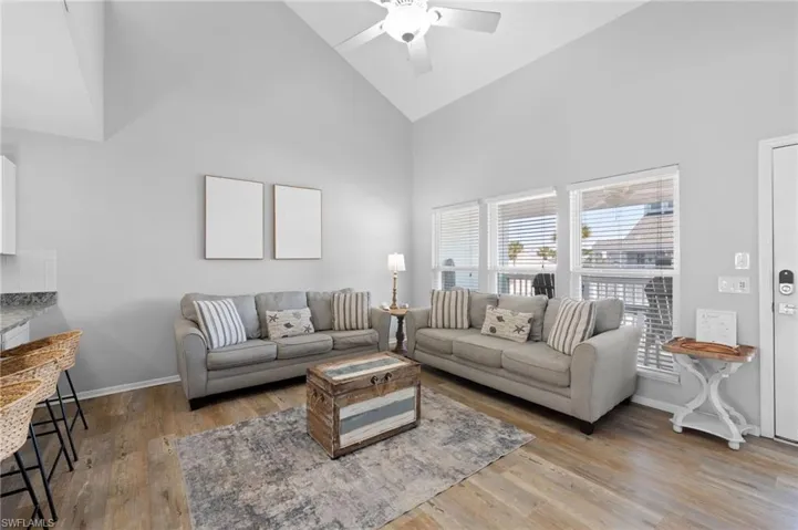 Living area with high vaulted ceiling, light wood-style floors, and ceiling fan