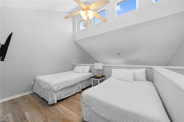 Bedroom featuring wood finished floors, ceiling fan, and a high ceiling