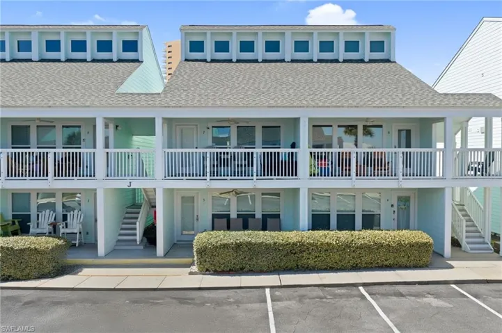 View of property with stairs and uncovered parking