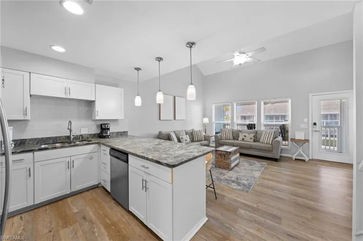 Kitchen featuring backsplash, white cabinetry, a peninsula, a kitchen bar, and light wood-style flooring
