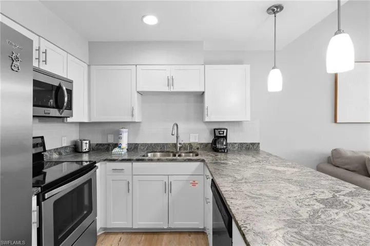 Kitchen with appliances with stainless steel finishes, white cabinets, tasteful backsplash, and recessed lighting