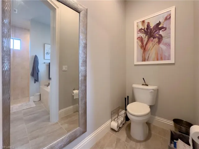 Bathroom featuring a bathing tub, tile flooring, and toilet