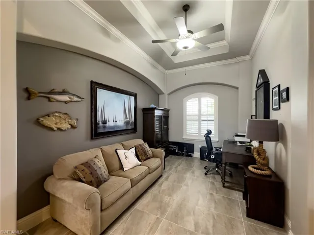 Office space featuring ceiling fan, ornamental molding, and a tray ceiling