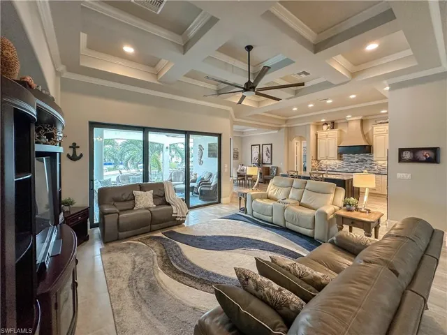 Living room with coffered ceiling detail, ceiling fan, crown molding & ceiling fan