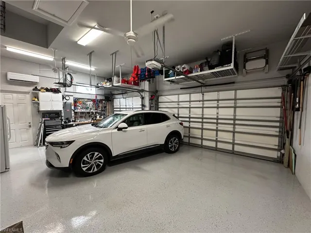 3 Car Garage featuring a garage door opener, a wall mounted air conditioner, and stainless steel fridge.Plenty of storage