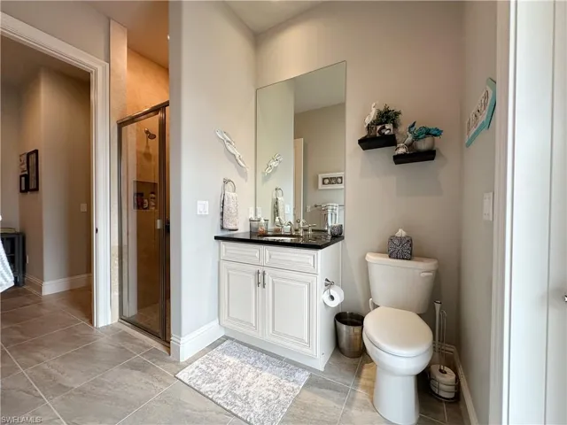 Pool/Guest bathroom featuring toilet, vanity, and a shower with shower door