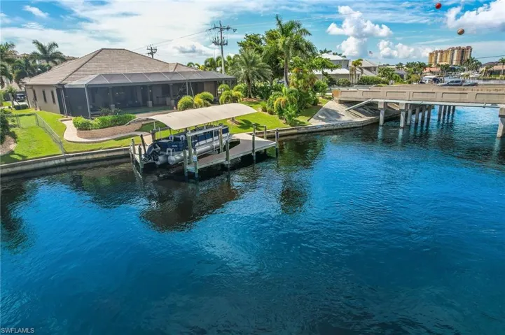 Dock area with a lanai, a water view, and a yard