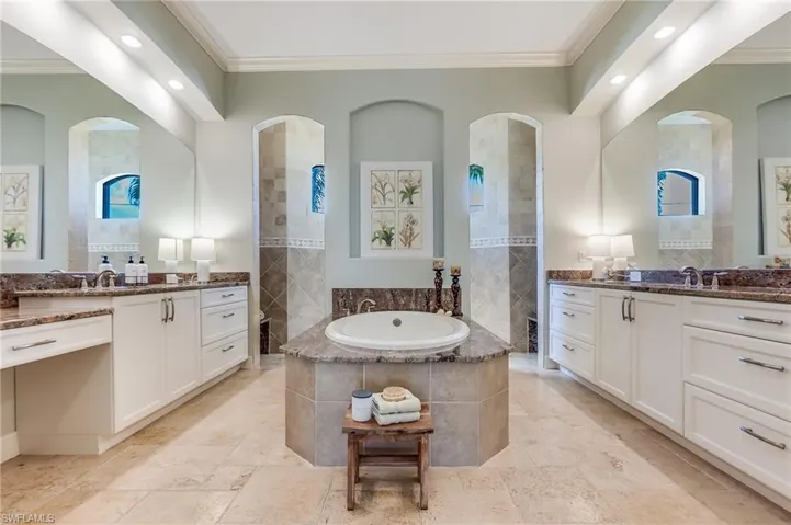 Bathroom featuring tiled bath, vanity, and ornamental molding