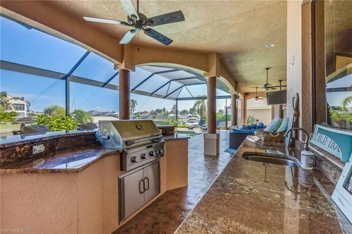 View of patio / terrace featuring glass enclosure, area for grilling, sink, and ceiling fan
