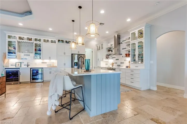 Kitchen with wine cooler, wall chimney range hood, decorative light fixtures, and white cabinets