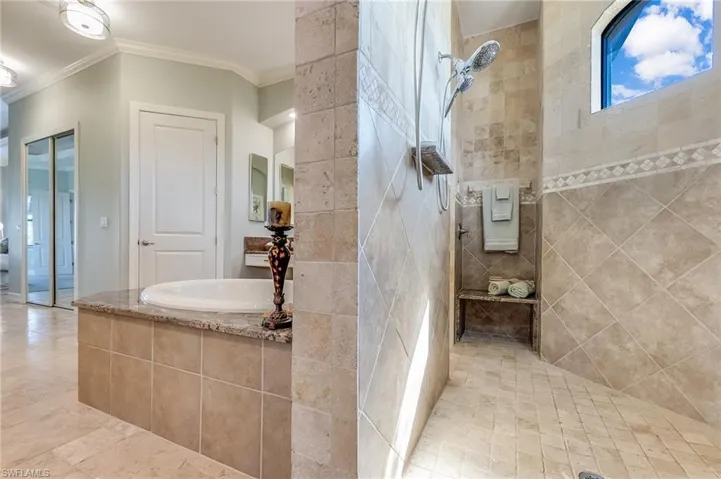 Bathroom with ornamental molding and separate shower and tub