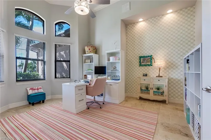 Office area featuring tile walls, ceiling fan, and a high ceiling
