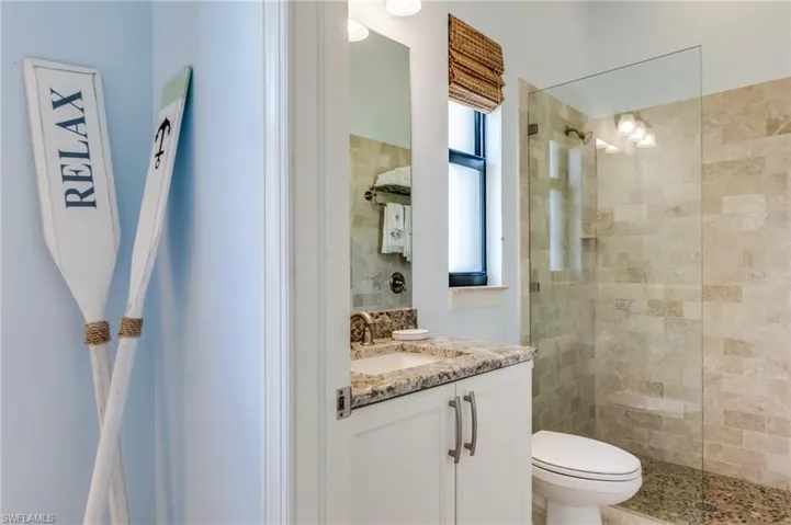 Bathroom with toilet, vanity, and a tile shower
