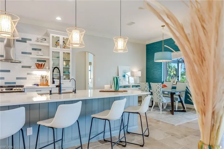 Kitchen with a kitchen breakfast bar, stainless steel range, crown molding, pendant lighting, and decorative backsplash