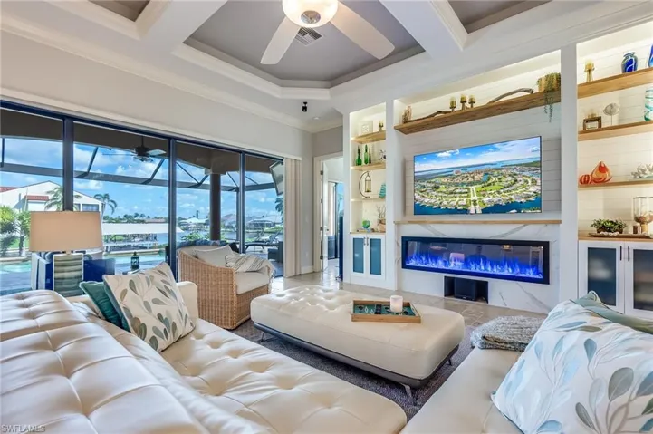 Living room featuring a premium fireplace, beam ceiling, crown molding, and coffered ceiling