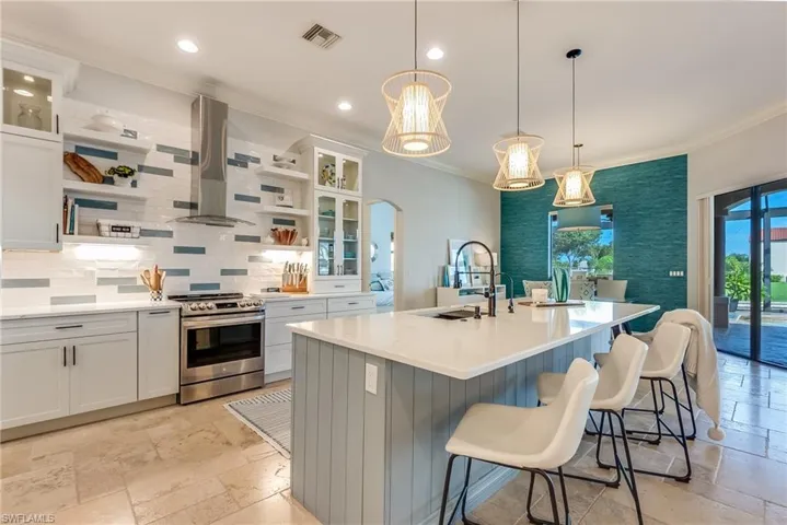 Kitchen with ventilation hood, a center island with sink, white cabinetry, sink, and stainless steel range oven