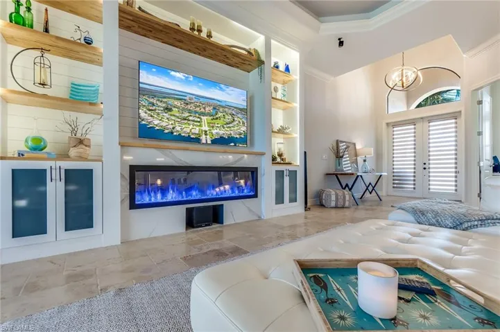 Living room with built in shelves, french doors, an inviting chandelier, and crown molding