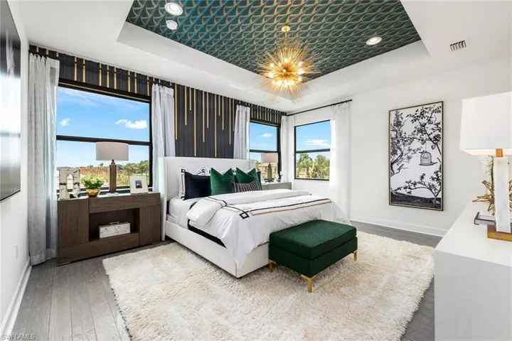 Bedroom featuring a notable chandelier, hardwood / wood-style floors, multiple windows, and a raised ceiling