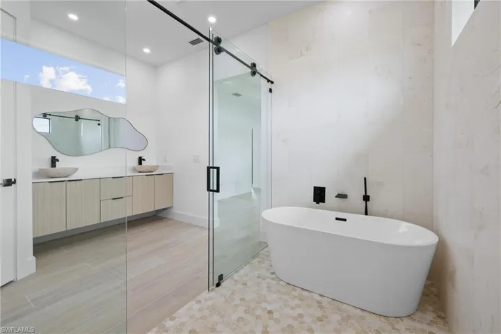 Bathroom featuring a stall shower, vanity, a spacious closet, wood finish floors, and recessed lighting