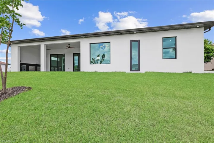 Back of house featuring stucco siding and a yard