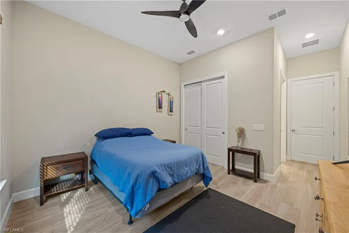 Bedroom with wood tiled floors, a closet, ceiling fan, and recessed lighting