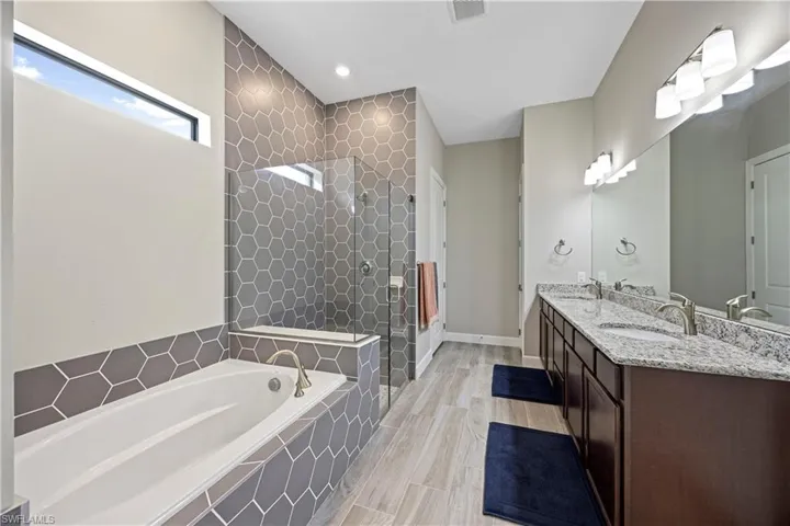 Bathroom with double vanity, a stall shower, a garden tub, and recessed lighting