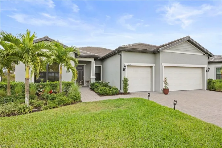 Ranch-style home with a front lawn, decorative driveway, stucco siding, an attached garage, and a tiled roof