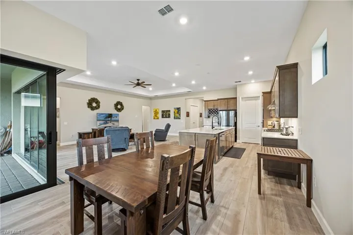 Dining area with a tray ceiling, recessed lighting, light wood-style flooring, and ceiling fan