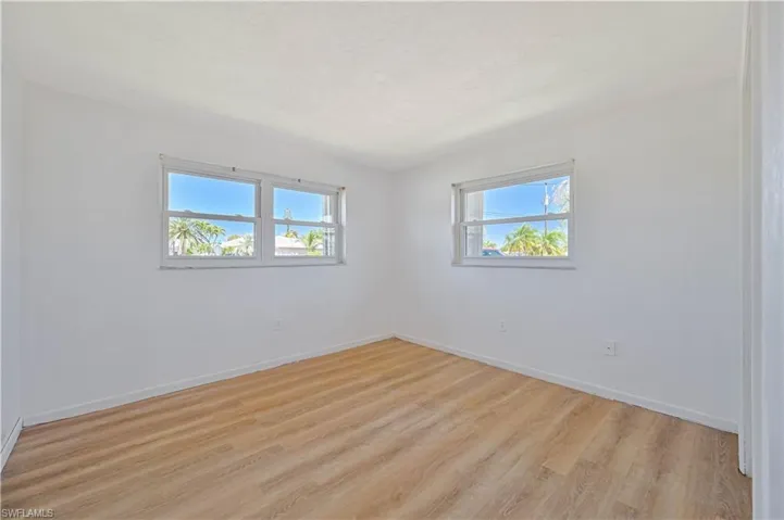 Spare room with baseboards, light wood-style floors, and a textured ceiling
