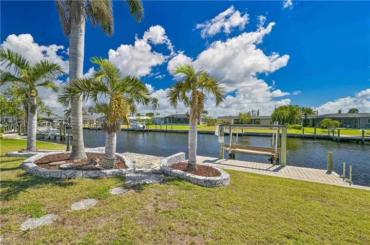 View of dock with boat lift, a yard, and a water view