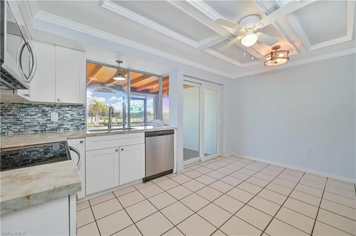 Kitchen featuring coffered ceiling, a sink, decorative backsplash, ceiling fan, and stainless steel appliances
