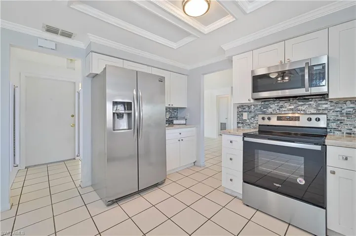 Kitchen with visible vents, ornamental molding, stainless steel appliances, light countertops, and light tile patterned floors
