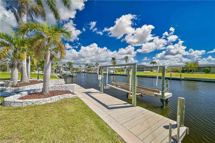 Dock area with boat lift, a yard, and a water view