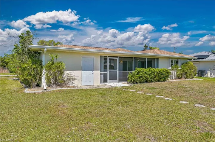 Back of property with a yard, a sunroom, and stucco siding