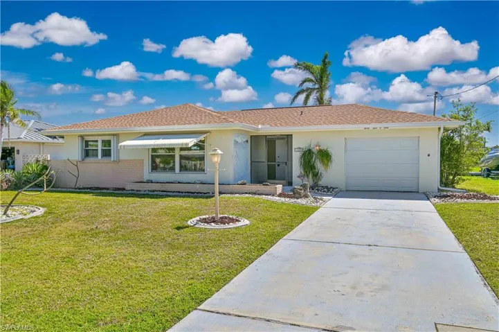 Ranch-style house featuring a garage, stucco siding, concrete driveway, and a front lawn