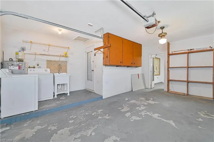 Garage with washer and dryer, a garage door opener, and water heater