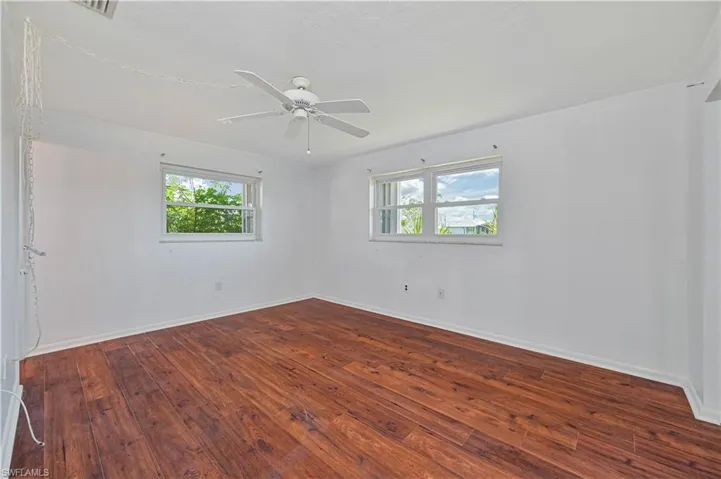Empty room with baseboards, a ceiling fan, and hardwood / wood-style flooring