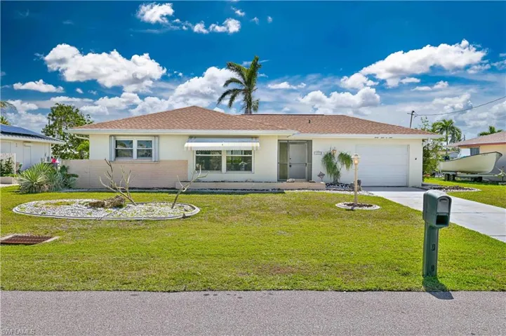 Ranch-style home with stucco siding, a garage, concrete driveway, and a front lawn